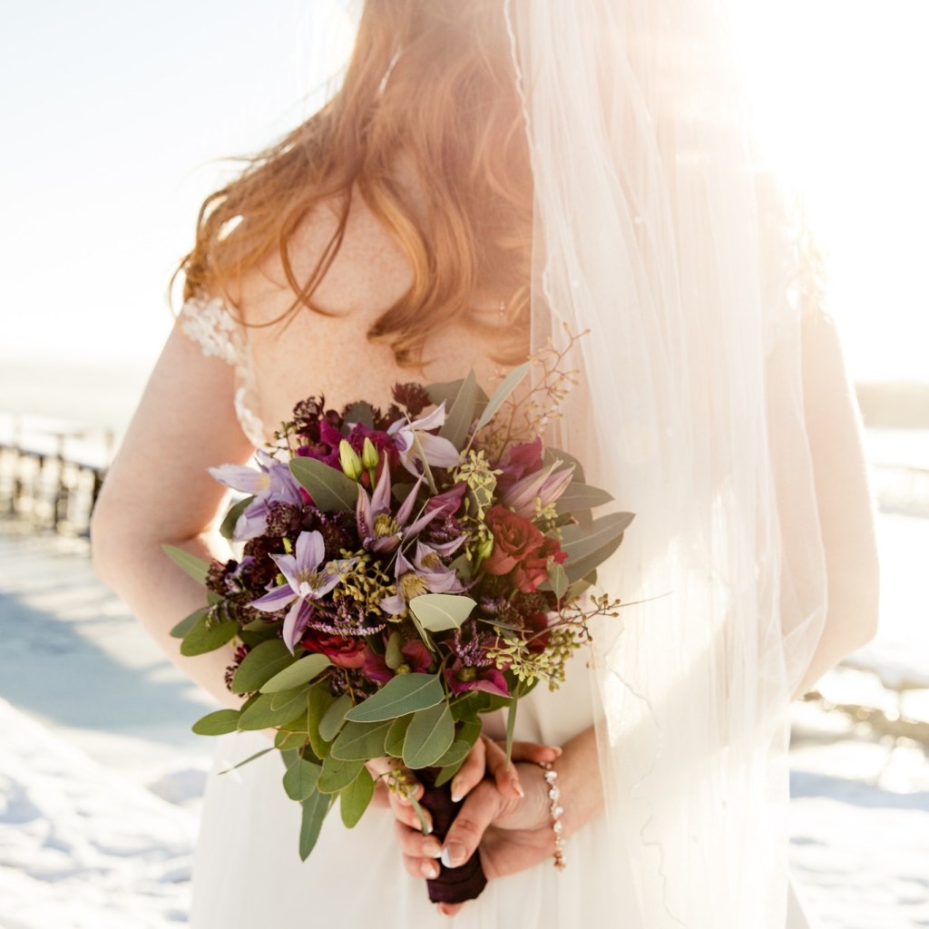 Braut im Winter auf Usedom hält bunten Brautstrauss fotografiert von Hochzeitsfotografin Usedom